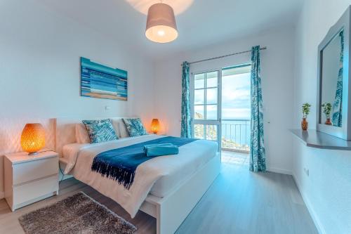 a bedroom with a bed and a large window at Casa Serena Apartments in Arco da Calheta