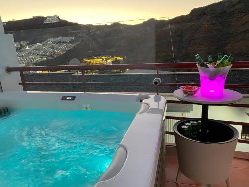 einen Pool mit einem Tisch und einem Getränk auf dem Balkon in der Unterkunft Villa Mogan Mall, con jacuzzi y PlayStation 5 in Puerto Rico de Gran Canaria
