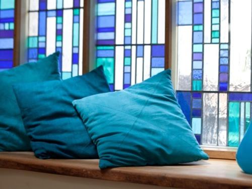 two blue pillows sitting on a bench in front of stained glass at Wild Garlic Rooms in Nailsworth