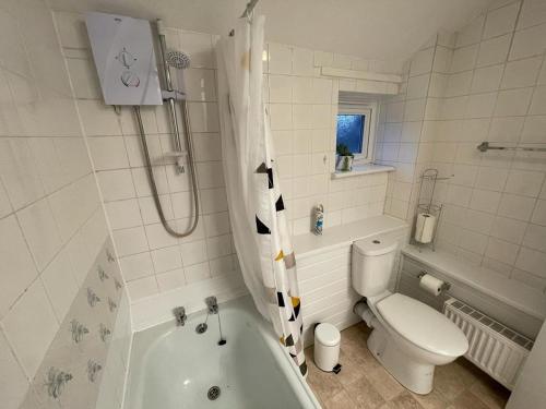 a bathroom with a tub and a toilet and a sink at 3-bedroom home with free parking in Canterbury
