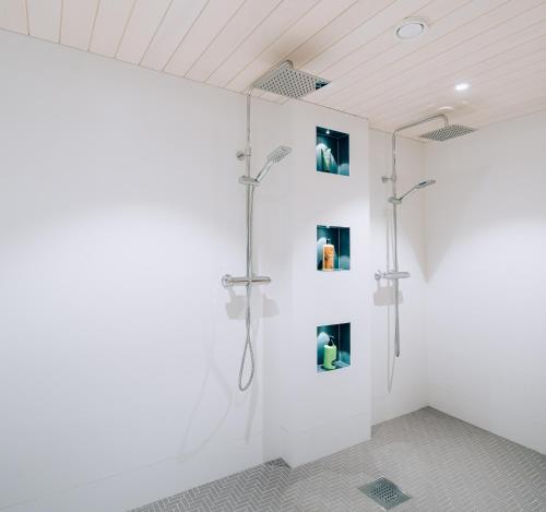 a white bathroom with a shower with pictures on the wall at Villa Snow White in Rovaniemi