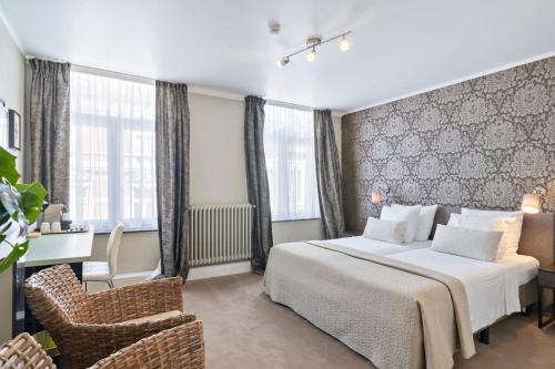 a hotel room with a bed and a chair at Hotel Belle-Vie in Sint-Truiden