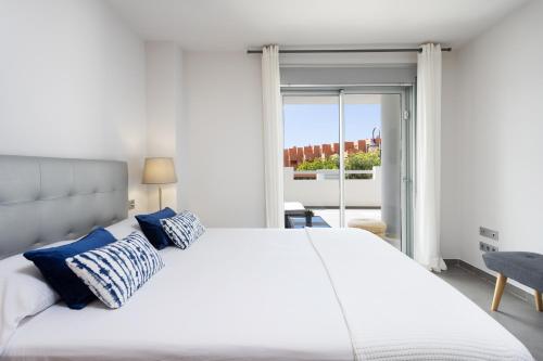 a bedroom with a large white bed with blue pillows at COSTA MAGALLANES BEACH LA TEJITA in Granadilla de Abona