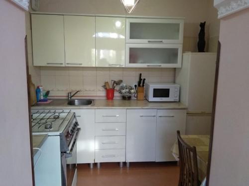 a kitchen with white cabinets and a sink and a microwave at Однокомнатная квартира у моря in Gagra