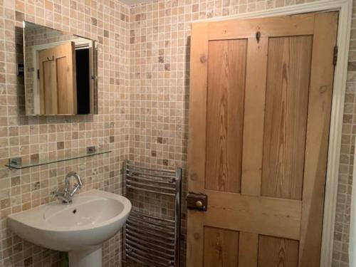 a bathroom with a sink and a wooden door at Cwmbach Cottage nr Hay on Wye in Glasbury