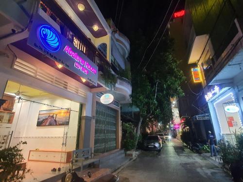 una calle de la ciudad por la noche con un cartel en un edificio en Abalone House Quy Nhơn, en Quy Nhon