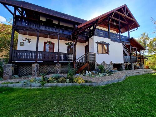 a large wooden house with a porch and a yard at Pensiunea Bogas in Praid