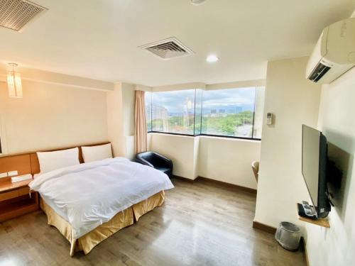 新竹市にあるRoyal Business Hotelのベッドと大きな窓が備わるホテルルームです。