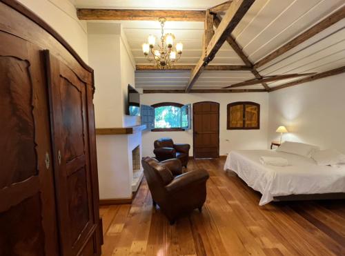 a bedroom with a bed and two chairs in it at Charqueada Santa Rita Pousada de Charme in Pelotas