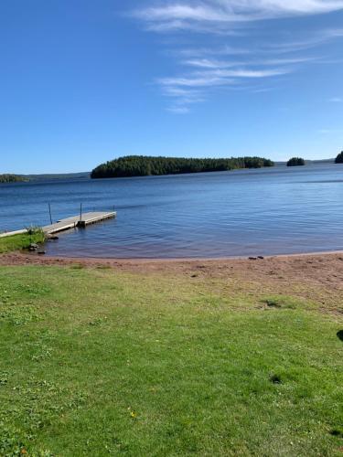 a body of water with a dock in the grass at Lakeside log cabin Främby Udde Falun in Falun