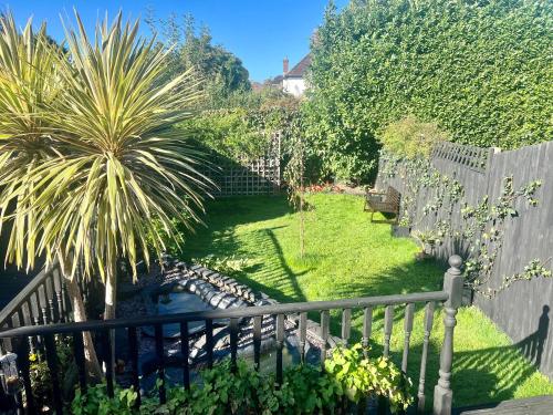 a garden with a fence and a palm tree at Beddington Park Lodge East in Wallington