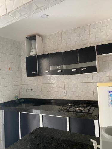 eine Küche mit schwarzen und weißen Schränken und einer Theke in der Unterkunft Apartamento familiar aconchegante in Maragogi