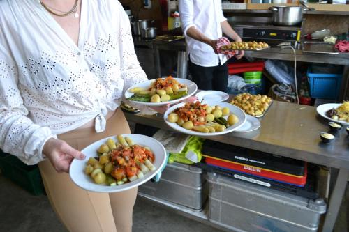 a woman holding three plates of food in a kitchen at lodge 61 hotel aan het water in Medemblik