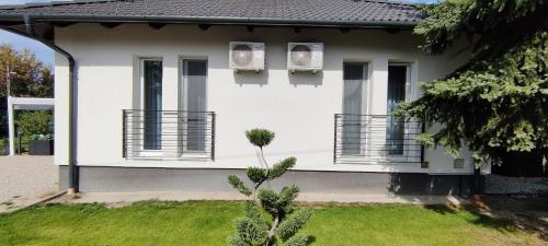 a white house with two windows and a yard at Rigó Apartman in Keszthely
