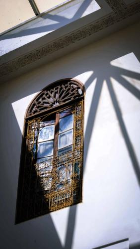 a window on a wall with a shadow of a cross at Palais Nazha Fes - Luxury Lodging in Fès