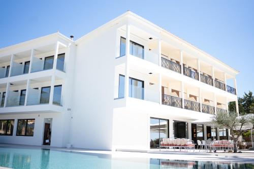 een wit gebouw met een zwembad ervoor bij PHEIA, Vriniotis Resorts in Katakolon