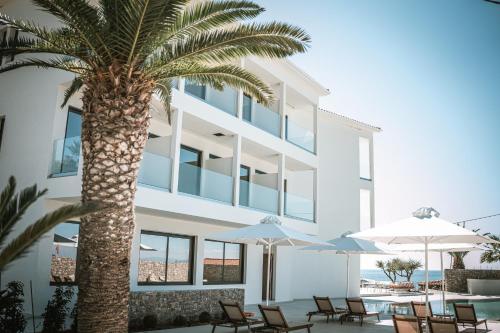 a palm tree in front of a building with chairs and umbrellas at PHEIA, Vriniotis Resorts in Katakolon