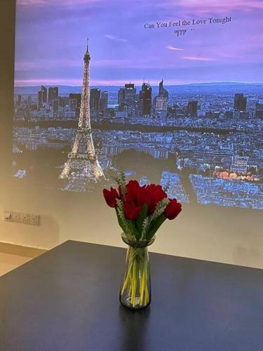 a vase of red roses sitting on a table with the eiffel tower at Setia Alam @ SCCC 3 Storey House in Shah Alam