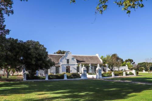 a large white house with a green lawn at Vergenoegd Löw Boutique Hotel & Spa in Cape Town