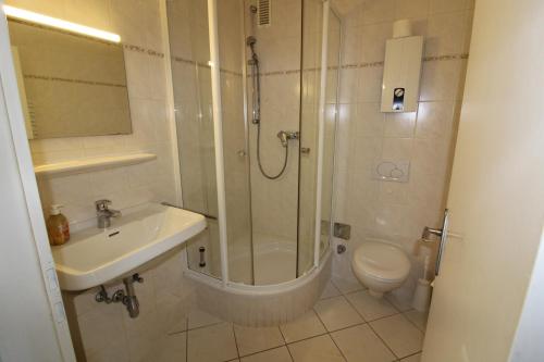 Un baño con ducha, lavabo e inodoro. en Haus Norderhoog Wohnung 54, en Westerland