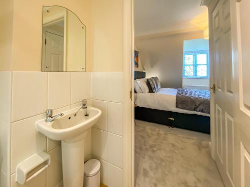 a bathroom with a sink and a bedroom with a bed at The Copperfield - Modern 4 Bed house with parking in Canterbury