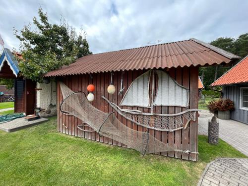 a wooden play house with a net in the yard at Poilsis Preiloje-91 in Neringa