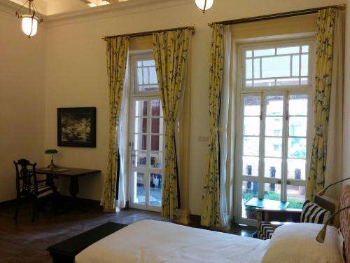 um quarto com cortinas amarelas, uma cama e uma secretária em The Harrington Residency em Calcutá