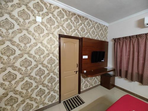 um quarto com uma porta, uma televisão e uma parede em Vyavahar lodge em Udupi