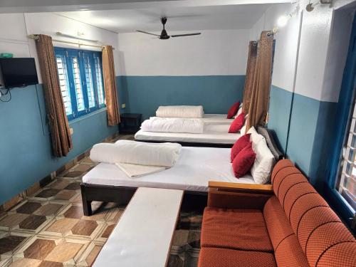 a room with three beds and a couch in it at R&R Guest House in Pokhara