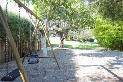 a swing set in a yard with a tree at Lavender farm house in Nafpaktos