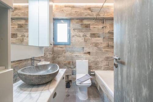 La salle de bains est pourvue d'un lavabo en pierre et d'une baignoire. dans l'établissement Seaside 2BR apartment in Varkiza 2mins walk from beach, à Vari
