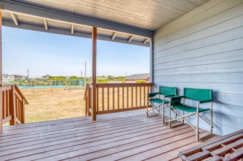 two chairs on a deck with a view of a field at Catamaran Cottage in Waldport