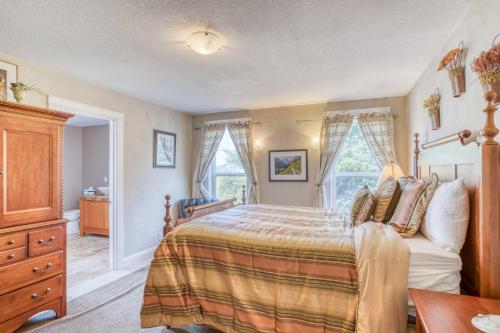 sypialnia z łóżkiem, komodą i oknami w obiekcie Catamaran Cottage w mieście Waldport
