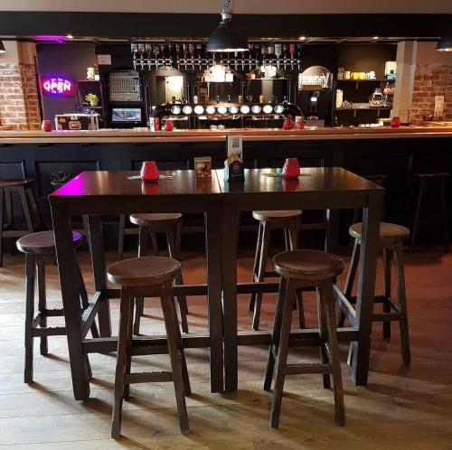 een houten tafel en krukken in een bar bij Hotel Café de Sport in Velden