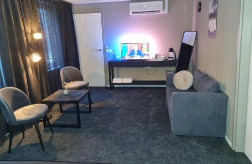 een woonkamer met een bank, stoelen en een tafel bij Hotel Café de Sport in Velden