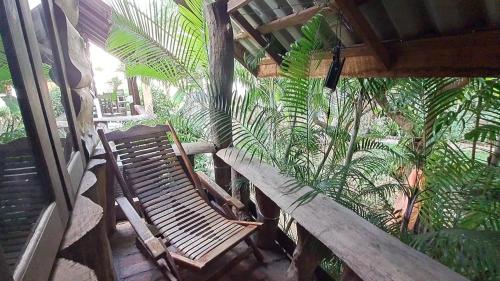 a porch with a wooden bench and palm trees at Sala Thongyon - Guest House in Savannakhet