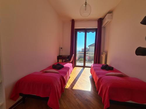 a row of red beds in a room with a window at Casa Erica by PortofinoVacanze in Rapallo