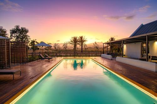 una piscina en una casa con una puesta de sol en el fondo en Vergenoegd Löw Boutique Hotel & Spa, en Ciudad del Cabo