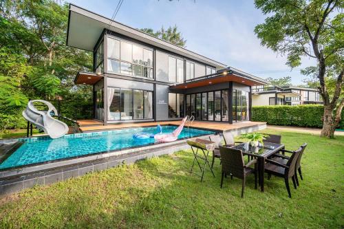 a house with a pool and a woman laying on the grass at AnB Loft poolvilla 3BR/3bath close Jomtian beach in Ban Huai Yai