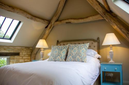 賽倫塞斯特的住宿－The Potting Shed, 5* Luxury escape Cirencester，卧室配有带两盏灯的白色床