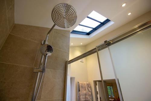 a shower with a shower head in a bathroom at The Potting Shed, 5* Luxury escape Cirencester in Cirencester
