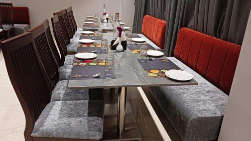 a long table in a restaurant with red chairs at Alaukik Hotel in Shirdi
