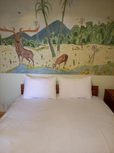 a bed with two pillows in front of a mural at SELINA GUEST HOUSE in Byurakan