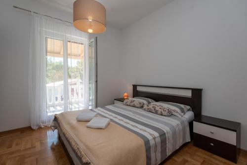 a bedroom with a bed and a large window at Apartman Tribunj in Tribunj