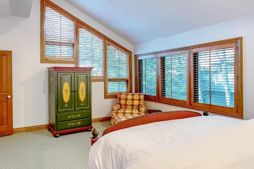 a bedroom with a bed and a chair and windows at Baldy View Lodge in Ketchum