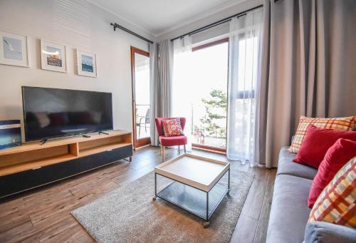 a living room with a couch and a tv at Apartamenty Na Wyspie - Baltic Park - Apartamenty z sypialnią i parkingiem - ul Uzdrowiskowa 24-34 in Świnoujście