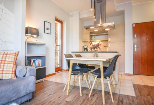 a kitchen and living room with a table and chairs at Apartamenty Na Wyspie - Baltic Park - Apartamenty z sypialnią i parkingiem - ul Uzdrowiskowa 24-34 in Świnoujście