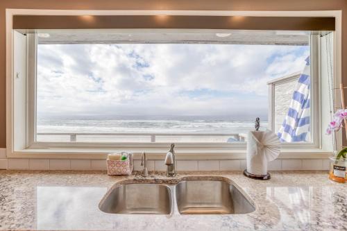 zlew kuchenny z dużym oknem z widokiem na ocean w obiekcie Pelican's Flight w mieście Rockaway Beach