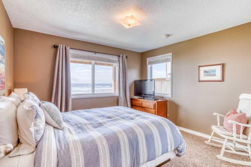 sypialnia z łóżkiem, telewizorem i oknem w obiekcie Pelican's Flight w mieście Rockaway Beach