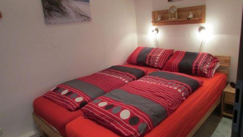 een rood bed met kussens op een kamer bij Haus Norderhoog Wohnung 47 in Westerland